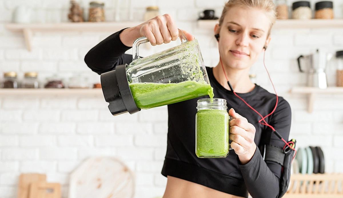 A woman pouring a green smoothie