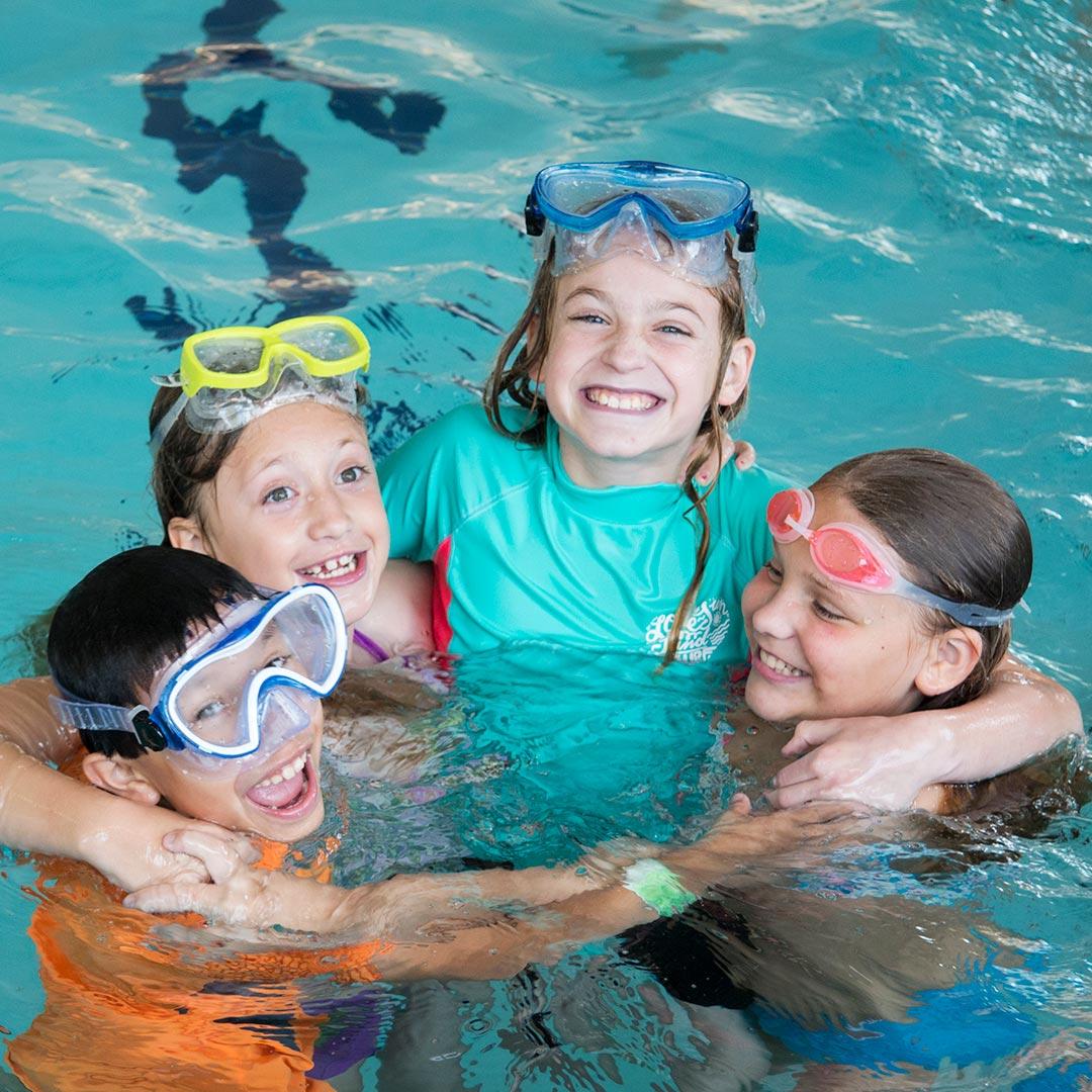 four children playing in an indoor pool